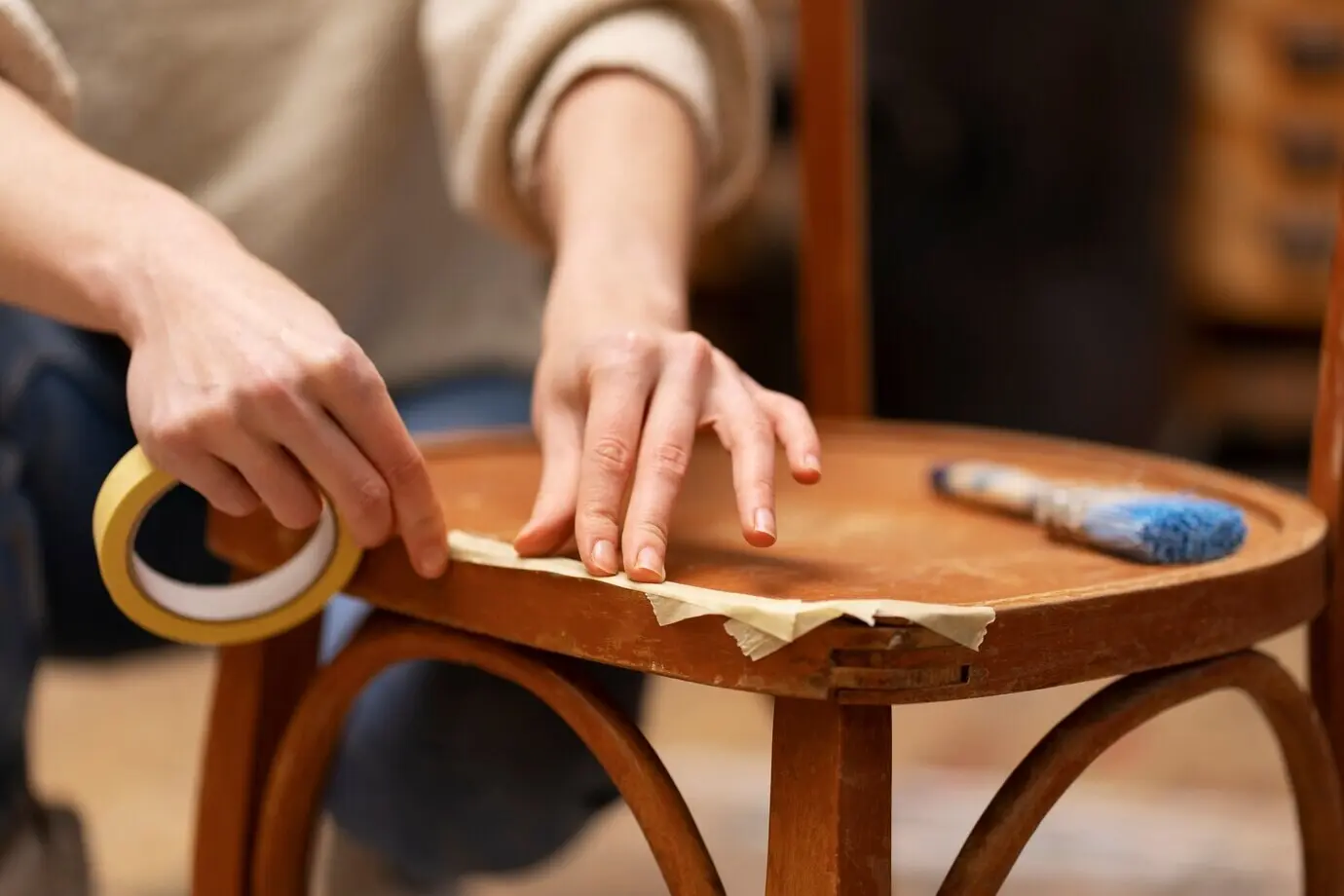 Front view of a woman restoring a wooden chair.