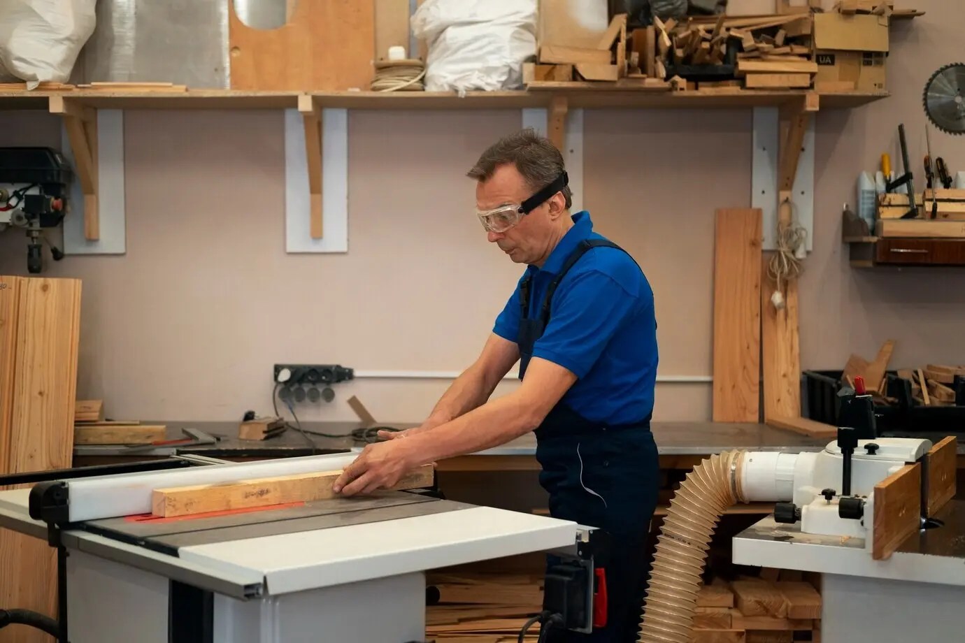 A man at work in his wood shop, with tools and equipment.